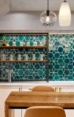 a dining room table and chairs in front of a wall with glass tiles on it