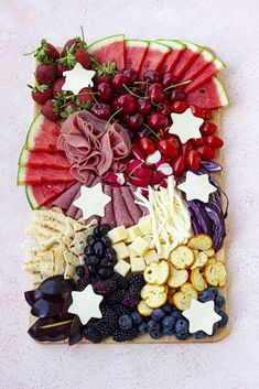 a watermelon slice with grapes, strawberries, cherries and crackers