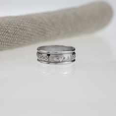 a wedding band with two hearts engraved on the side, sitting next to a piece of fabric