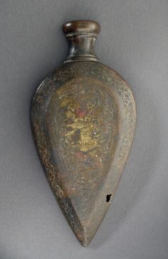 an old metal vase is hanging on the wall in front of a gray background with gold and red designs