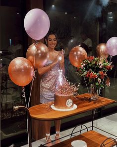 a woman holding balloons in front of a table