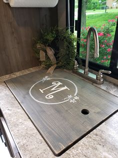 a wooden cutting board sitting on top of a kitchen counter next to a sink and window