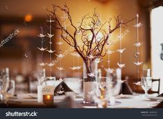 a vase filled with branches and paper birds hanging from it's sides on top of a table