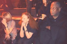 two people sitting next to each other in front of a crowd at a fashion show