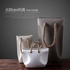 three white and gray bags with rope handles on top of a wooden table next to each other