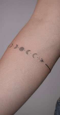 a woman's arm with phases of the moon and stars tattoo on her left arm