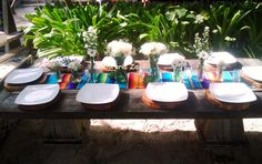 the table is set with plates and vases on it, along with flower arrangements