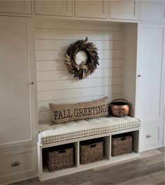 a white bench with baskets underneath it and a wreath on the wall above it that says fall greetings