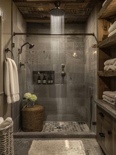 a walk in shower sitting inside of a bathroom next to a wooden shelf filled with towels