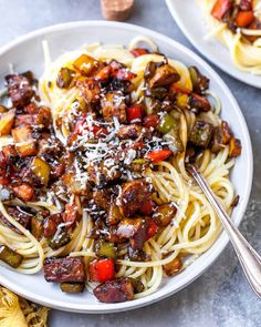 two plates of spaghetti with meat and vegetables