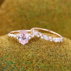 two wedding rings sitting on top of a moss covered ground with grass in the background