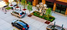 an aerial view of cars parked in front of a building with a sculpture on the side