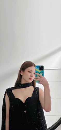 a woman taking a selfie in front of a mirror wearing a black dress with cut out shoulders