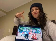 a woman pointing to the screen on her laptop computer while wearing a beanie hat