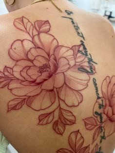 the back of a woman's shoulder with flowers on it and words written in cursive writing