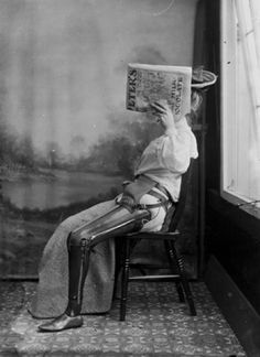 an old black and white photo of a woman sitting in a chair reading a book