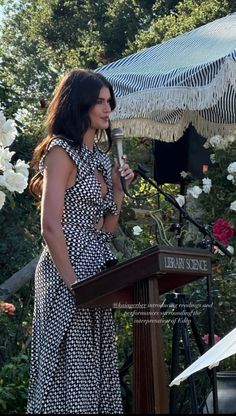 a woman standing at a podium in front of an umbrella