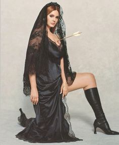 a woman in a black dress and veil holding a wand