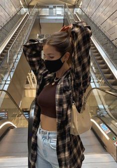 a woman wearing a face mask while walking down an escalator with her hand on her head