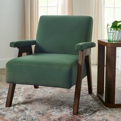 a green chair sitting on top of a rug next to a table with a potted plant