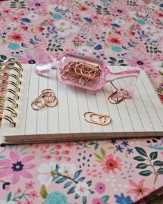 an open notebook with paper clips and ring binders sitting on a flowered tablecloth