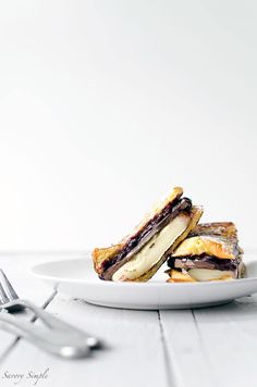 two grilled sandwiches on a white plate with silverware