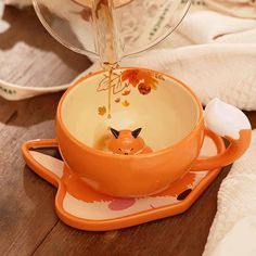 an orange cup is being filled with liquid from a faucet in the shape of a fox