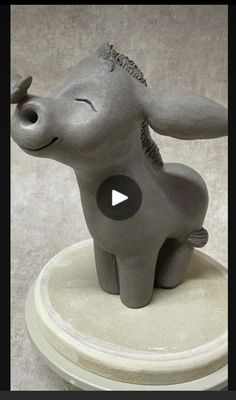 an elephant figurine sitting on top of a white table next to a gray wall