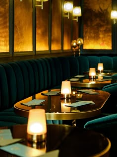 an empty restaurant with green velvet booths and lit candles on the tables in front of them