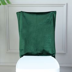 a green pillow sitting on top of a white chair next to a potted plant