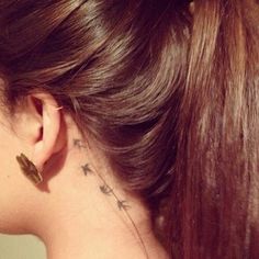 the back of a woman's neck with small stars on her left side ear