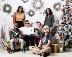 a group of people sitting next to each other in front of a christmas tree