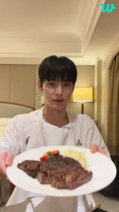 a man holding a plate with meat and vegetables on it