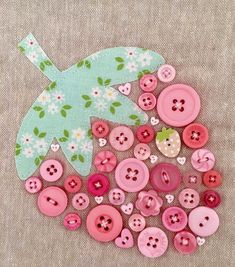 some pink and green buttons sitting on top of a piece of fabric