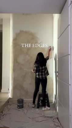 a woman painting the edge of a wall in a room that is being painted white