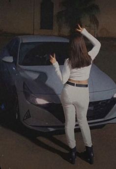 a woman standing next to a silver sports car