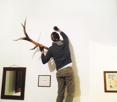 a man standing on top of a wooden floor next to a deer's antler