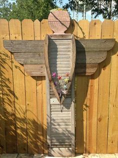 a wooden cross made out of shutters in the shape of an angel with flowers on it