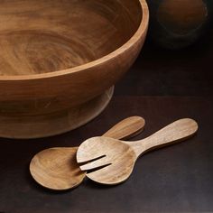 two wooden utensils sitting next to each other in front of a large bowl