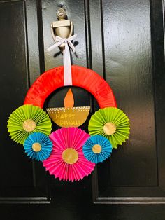 a colorful wreath on the front door with paper fans around it and a lit candle