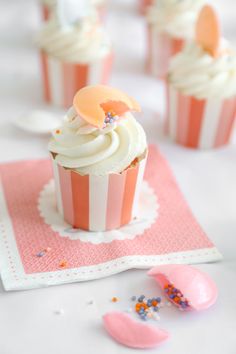 cupcakes with white frosting and sprinkles on a pink napkin