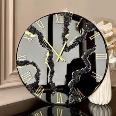 a black and gold clock sitting on top of a table next to a vase with flowers