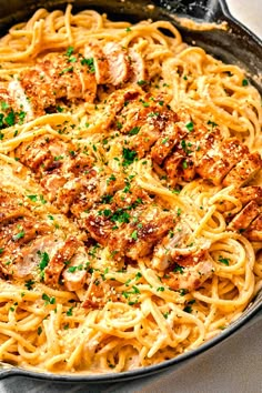 a skillet filled with pasta topped with meat and parsley