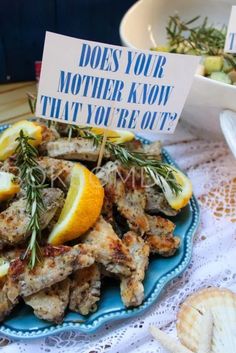 a blue plate topped with chicken wings covered in lemons and rosemary next to a sign that says does your mother know that you'reot?