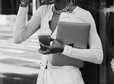 a woman holding a laptop and drinking coffee