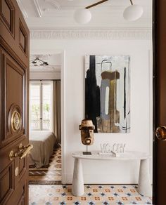 an entry way with a white table and paintings on the wall, along with two brown doors