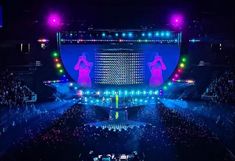 the stage is lit up with purple and green lights, as well as two women standing on each side