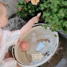 a toddler playing with toys in a potted plant