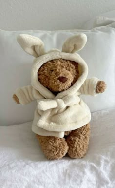 a teddy bear in a bunny costume on a bed