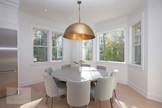 a dining room table with chairs and a light fixture hanging from it's ceiling